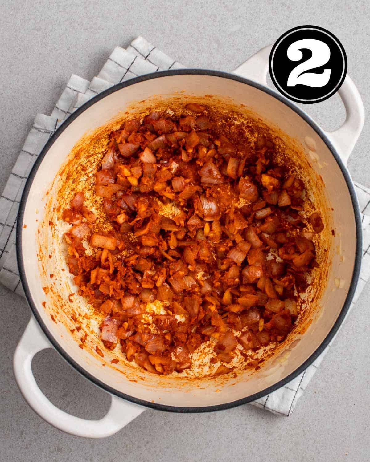 Curry paste, ginger, garlic, and onion in a Dutch oven on a folded white teacloth.