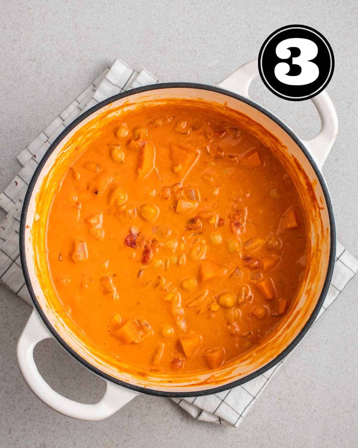 A pot of sweet potato and chickpea curry on a folded white teacloth.