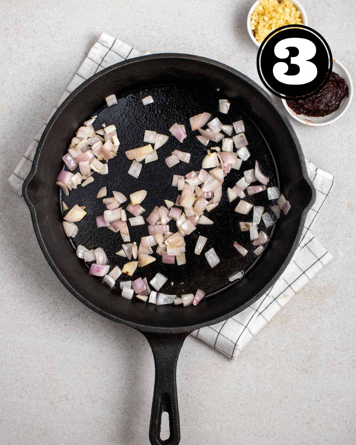 Cooked onion in a cast iron skillet with a folded white teacloth. 