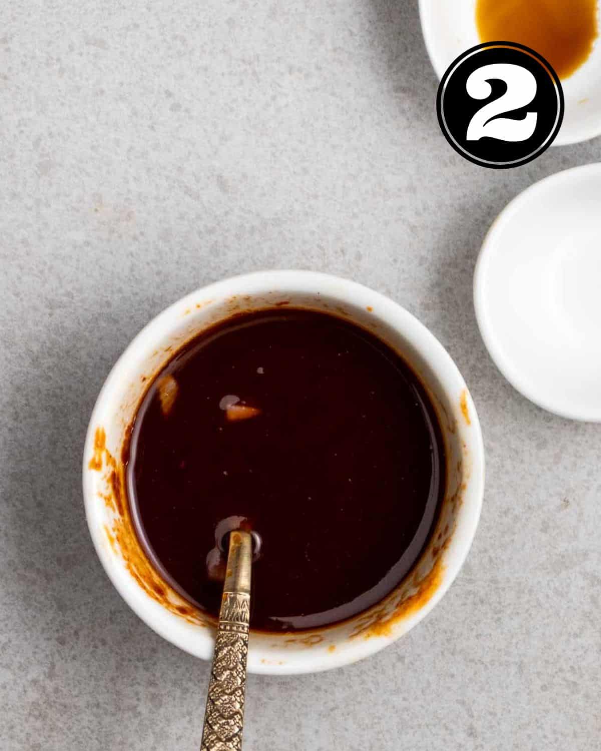 Gochujang sauce in a ramekin with a spoon beside.