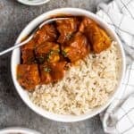 Tofu curry served with rice in a bowl served with a spoon.