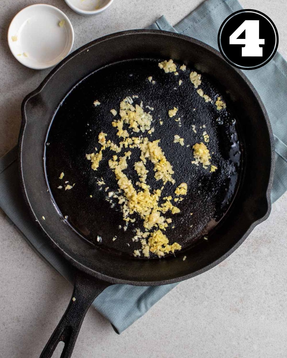 Fried ginger and garlic in a cast iron skillet on a blue folded teacloth.