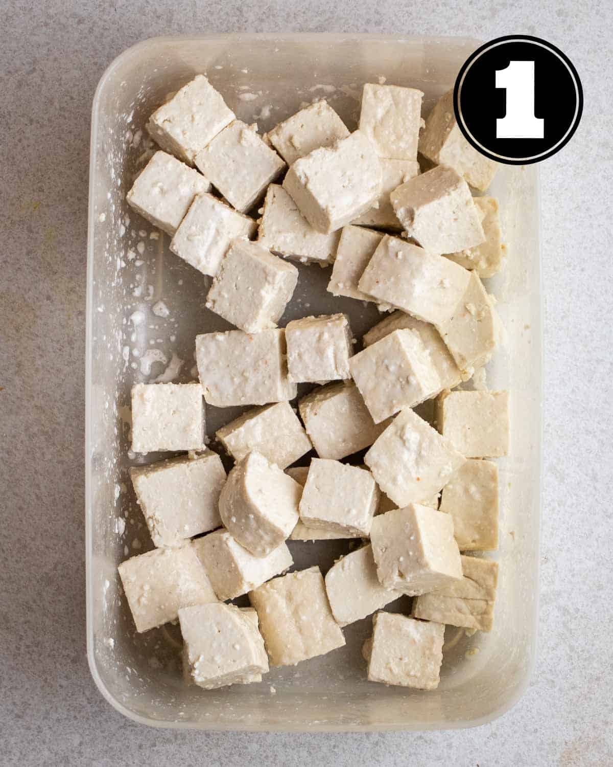 Tofu coated with cornstarch in a container.
