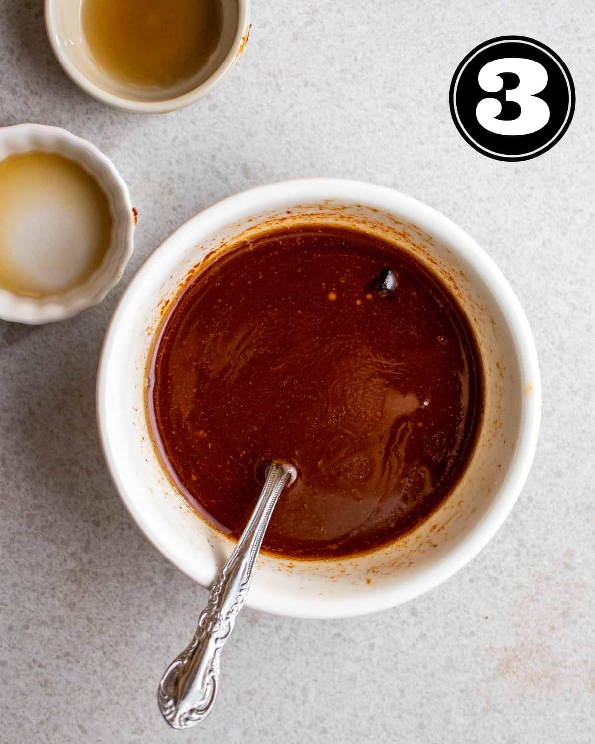 Gochujang sauce in a ramekin with a teaspoon beside with 2 empty sauce dishes beside.