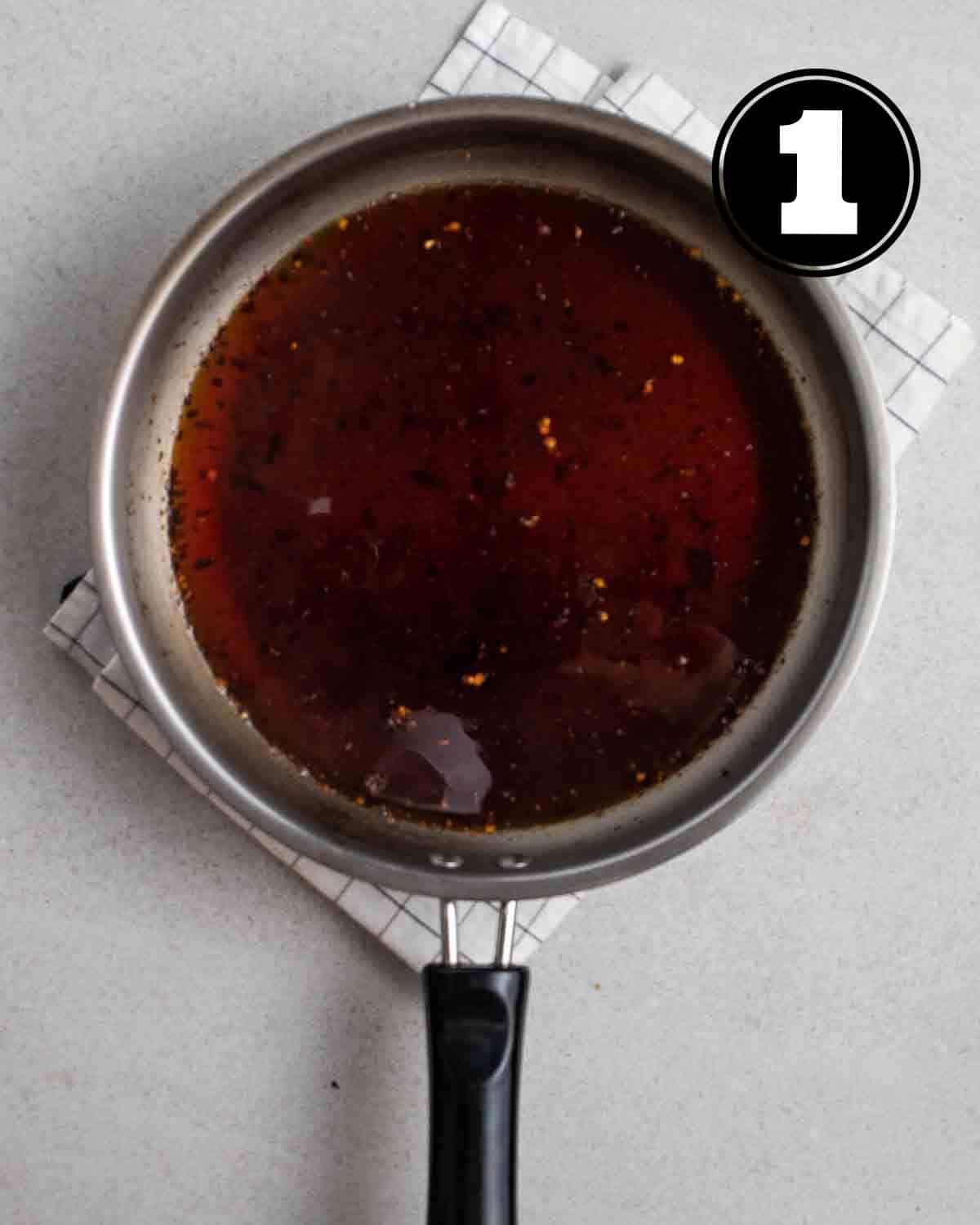 Ingredients for teriyaki sauce in a saucepan on a white folded checkered teacloth.