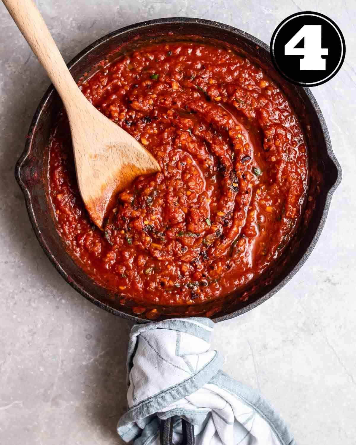 A pan of cooked vegan tomato sauce with a wooden spatula beside.