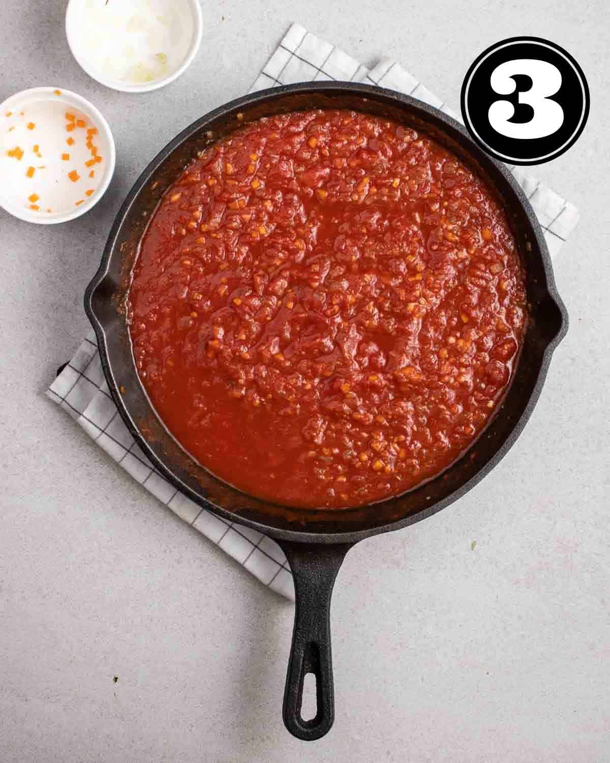 Adding crushed tomatoes into a pan on a folded white checkered teacloth.