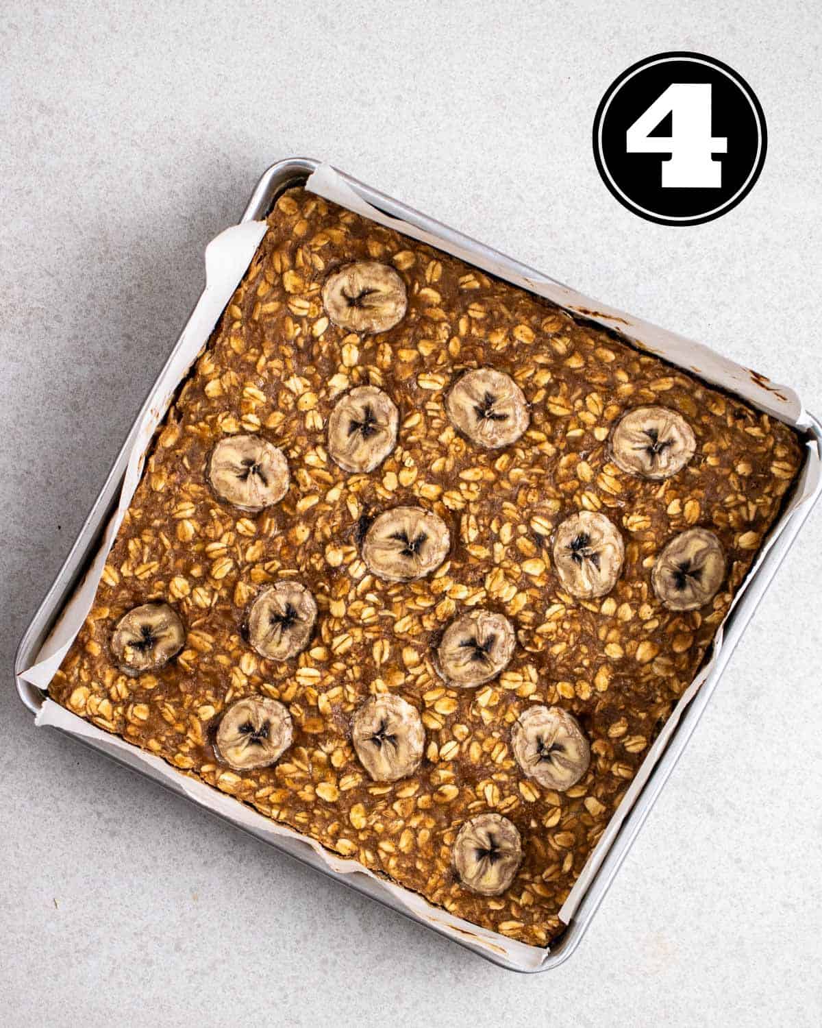 Baked banana flapjack in a baking pan lined with parchment paper.