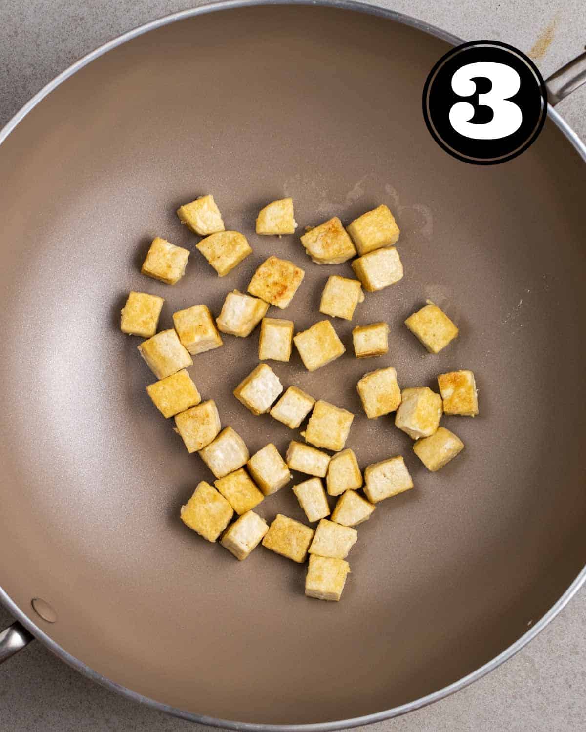 Fried tofu cubes in a wok.