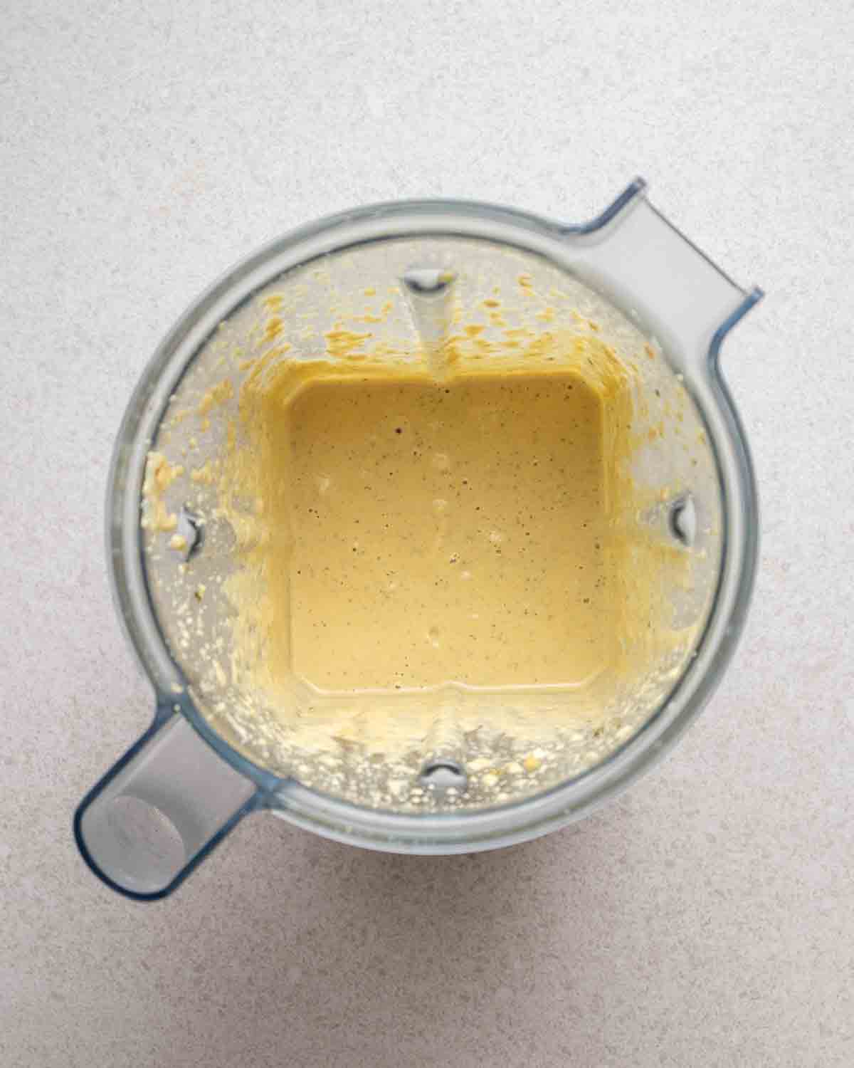 Salad dressing in a blender on a grey background.