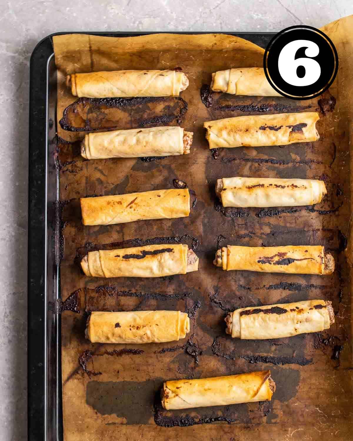 Baked lumpia on a lined baking sheet.