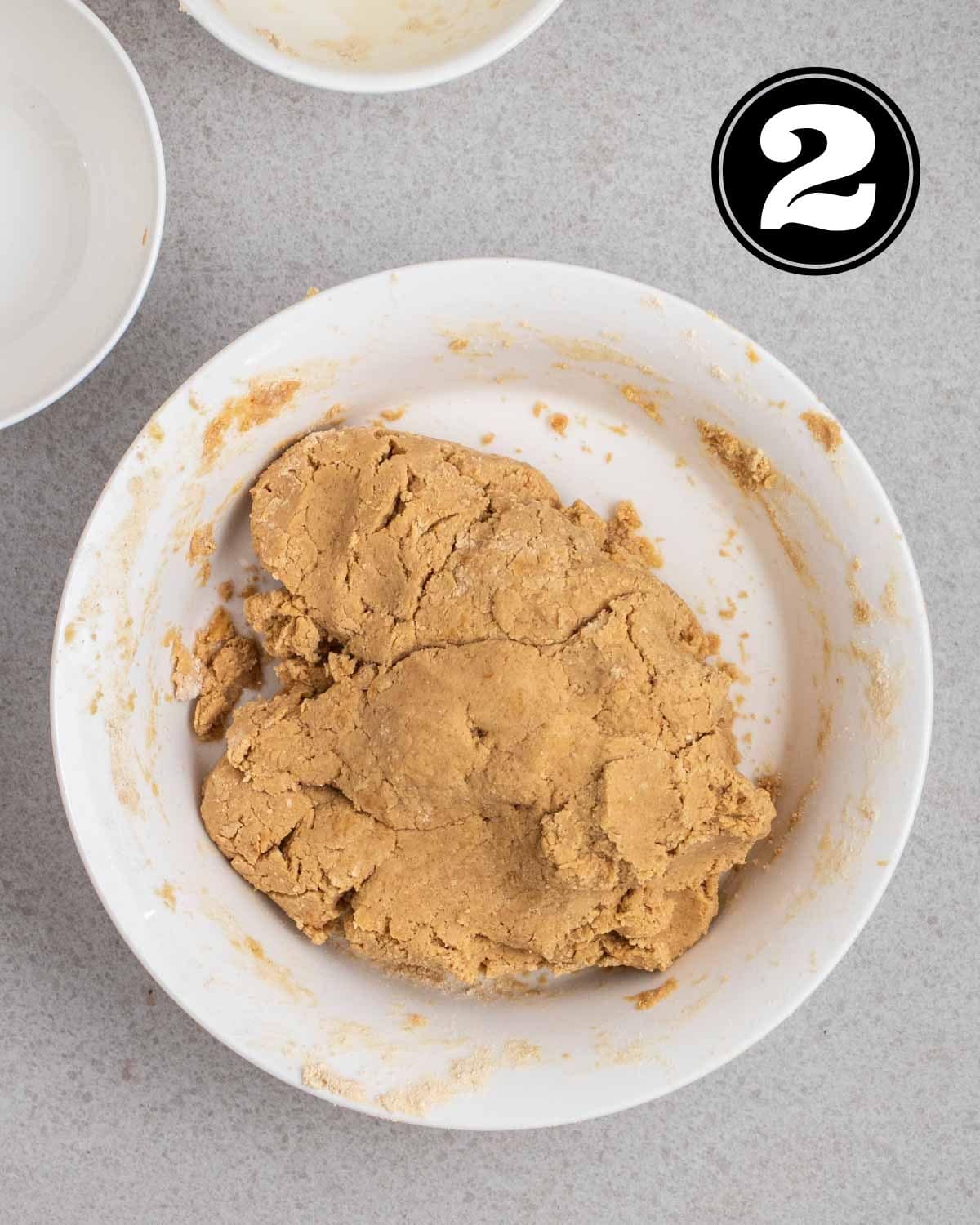 Dough for protein bar in a white bowl with 2 ramekins beside.