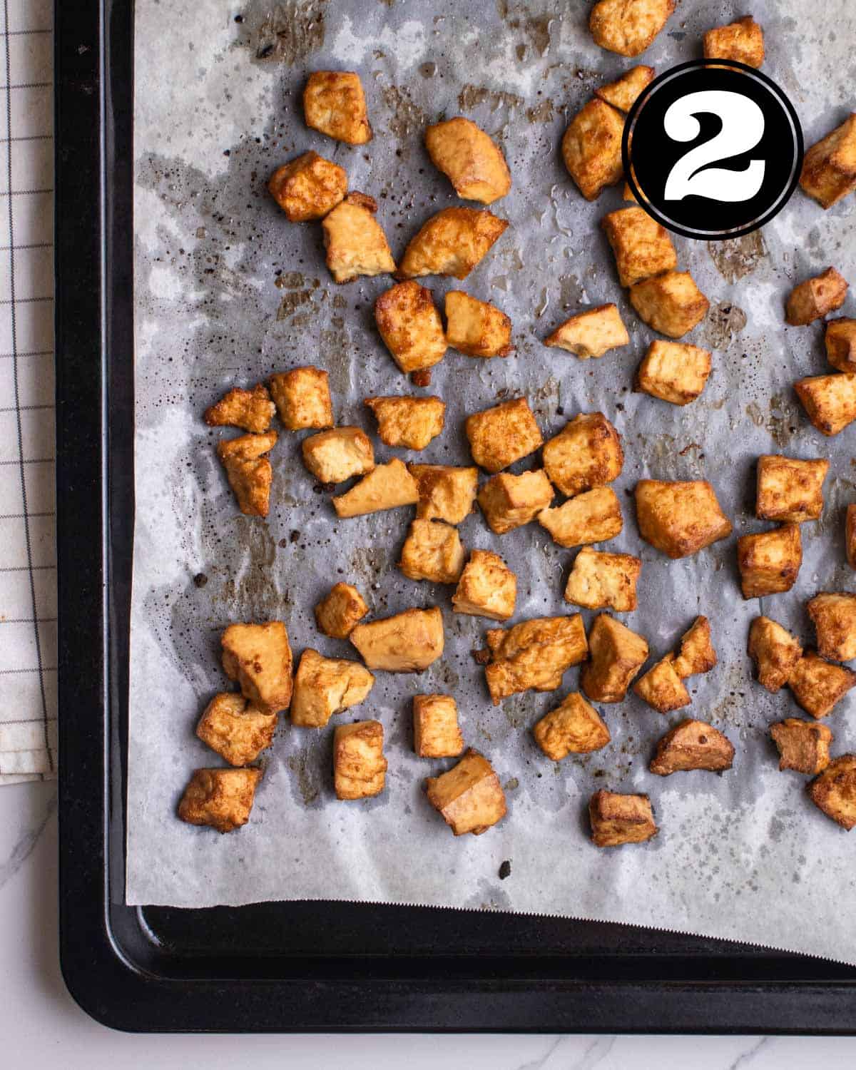 Baked tofu in a baking pan lined with parchment paper.