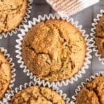 Applesauce zucchini muffins arranged on a cooling tray lined with parchment paper.