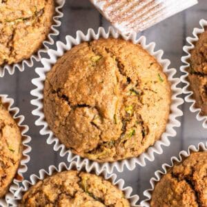 Applesauce zucchini muffins arranged on a cooling tray lined with parchment paper.