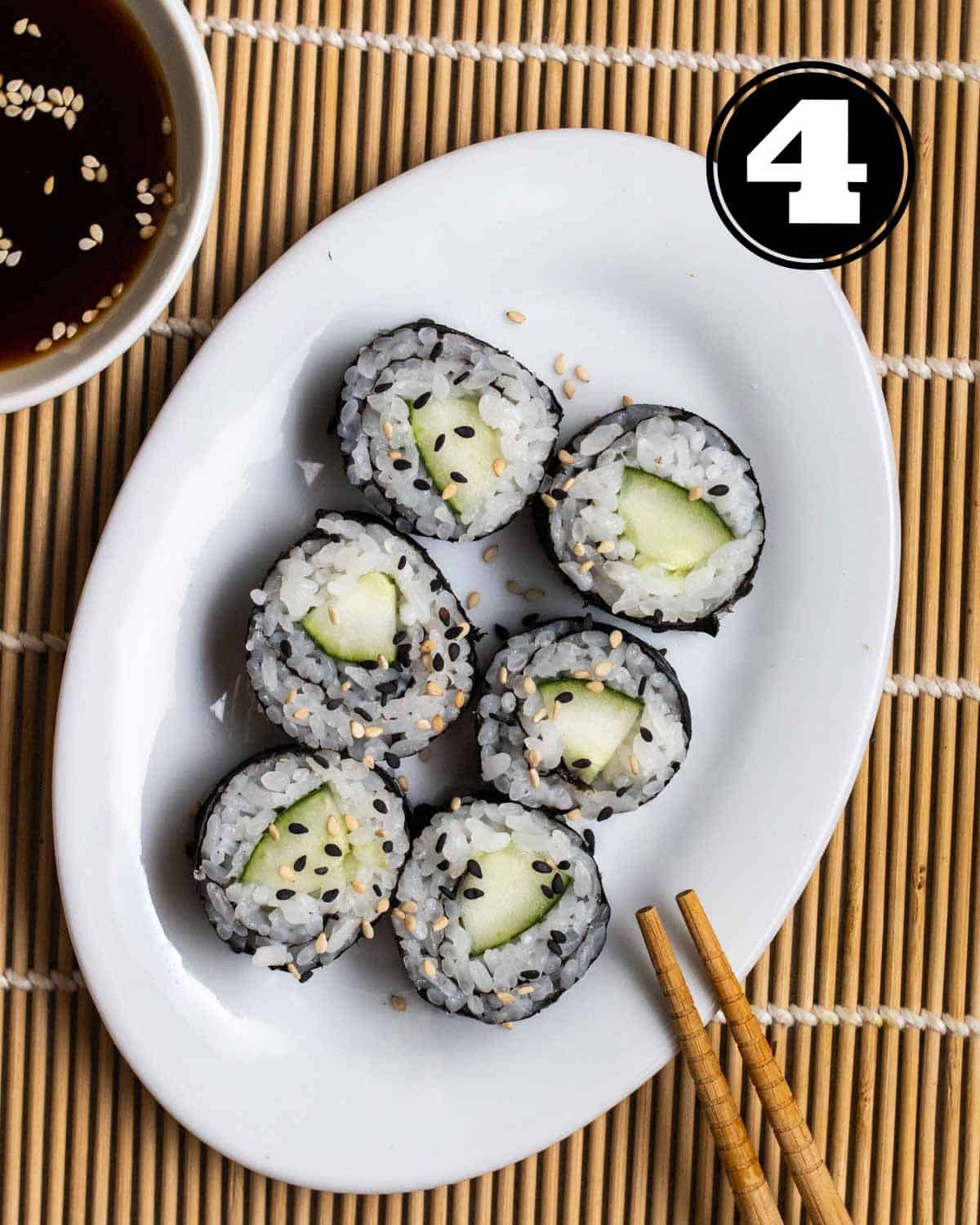 Slices of kappa maki on a plate with chopsticks beside.