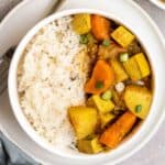 Bowl of rice and curry served on a plate with a fork beside.