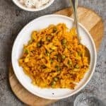 Plate of cabbage curry serve with spoon with a bowl of rice beside.