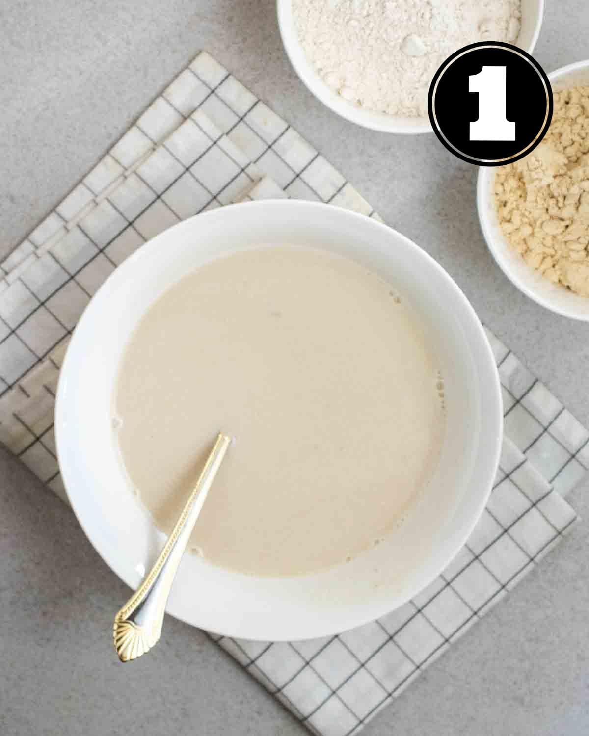 Wet ingredients for pancakes in a white bowl with a fork beside.