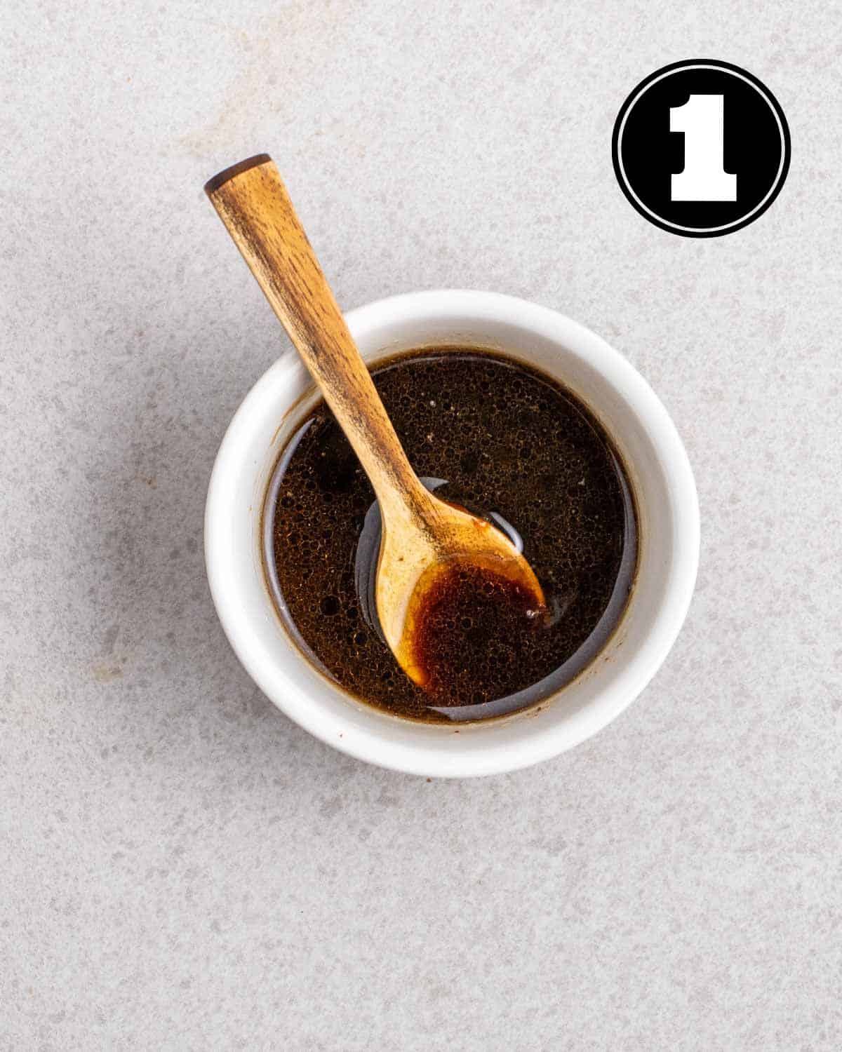 Sauce for tofu sisig in a ramekin with a wooden spoon beside.