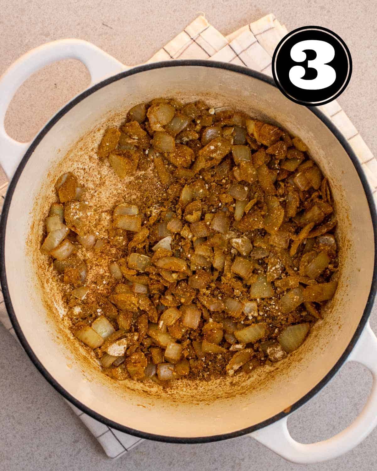 Onion, garlic, and curry powder in a white Dutch oven.