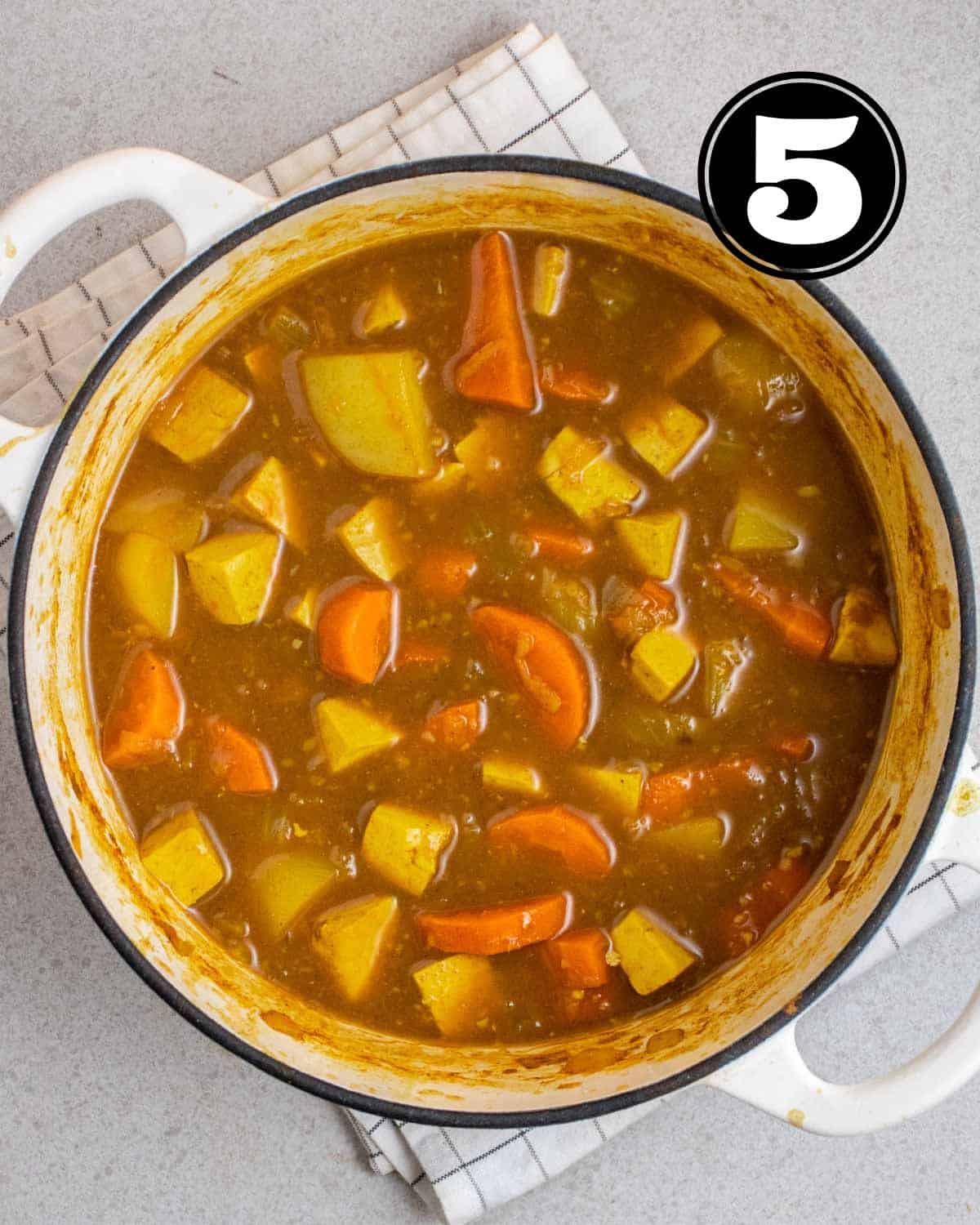 A pot of Japanese curry on a white folded checkered teacloth.
