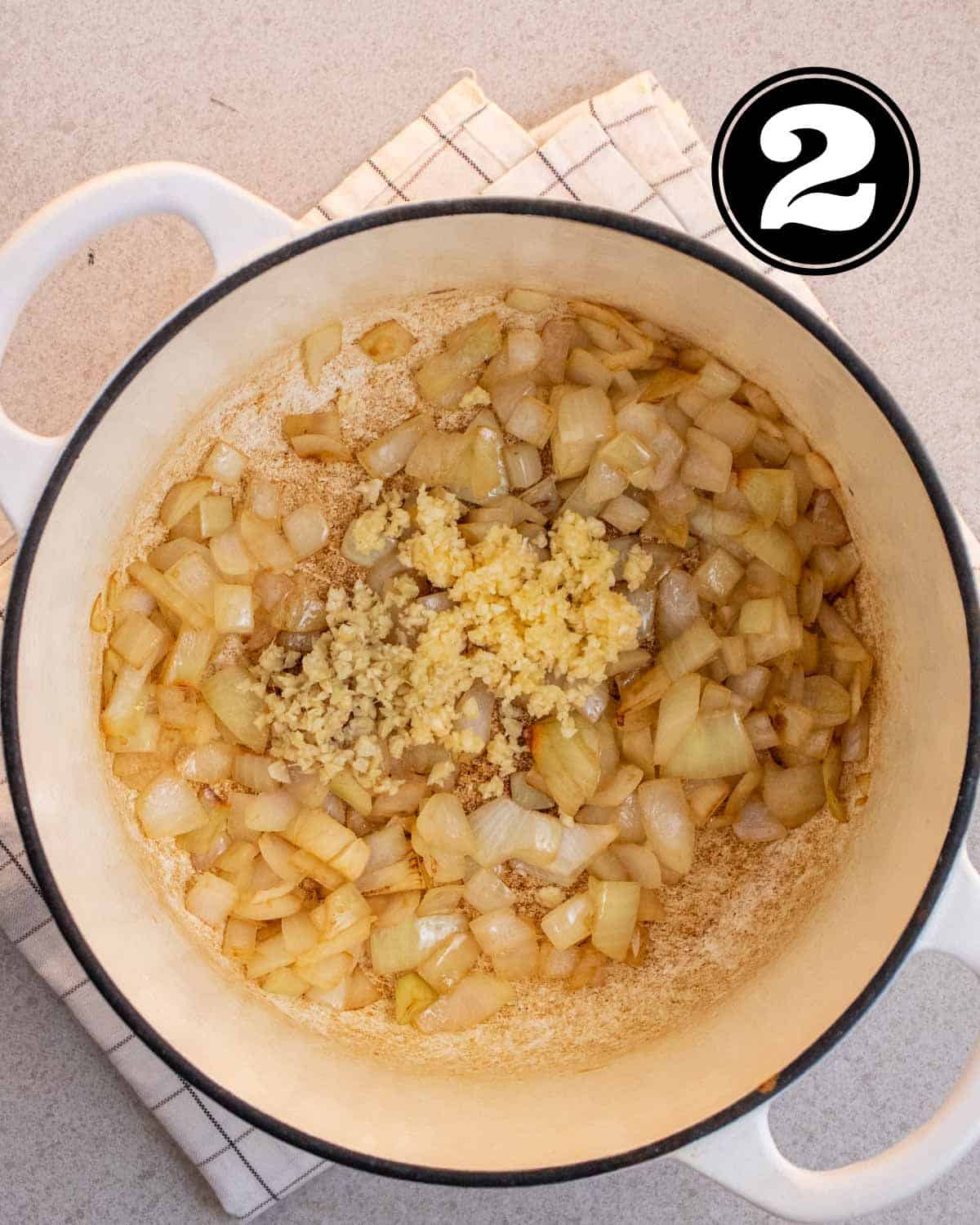Cooked onion and garlic in a white Dutch oven.