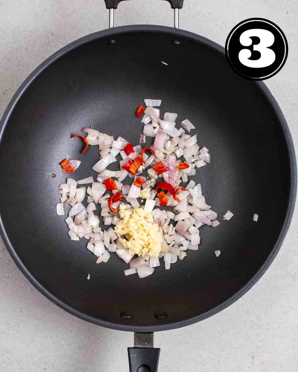 Frying onion, chilies, and garlic in a wok.