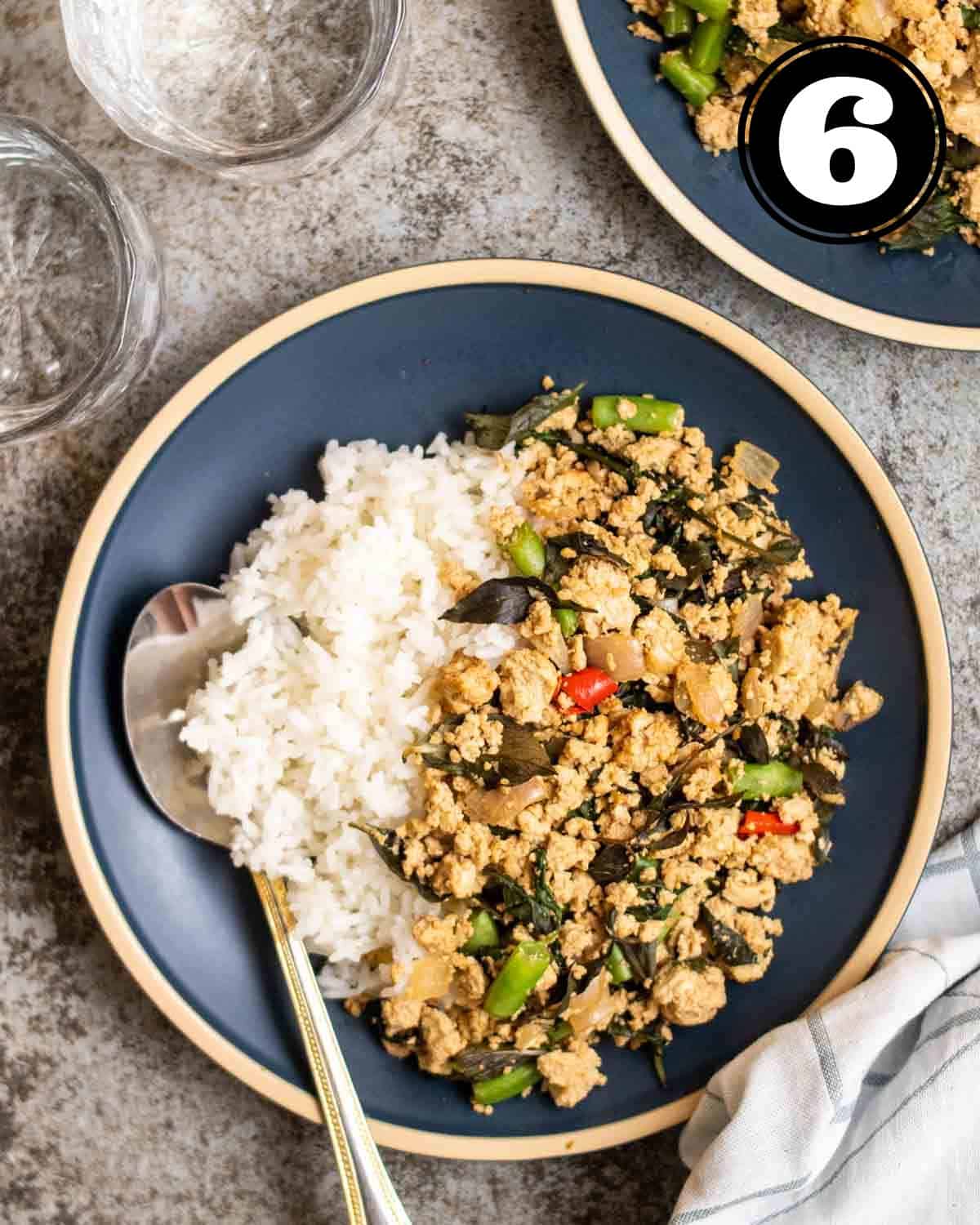 a plate of Thai basil tofu served with rice and a spoon beside.