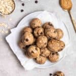 A plate of protein balls with oats and a spoonful of peanut butter beside.