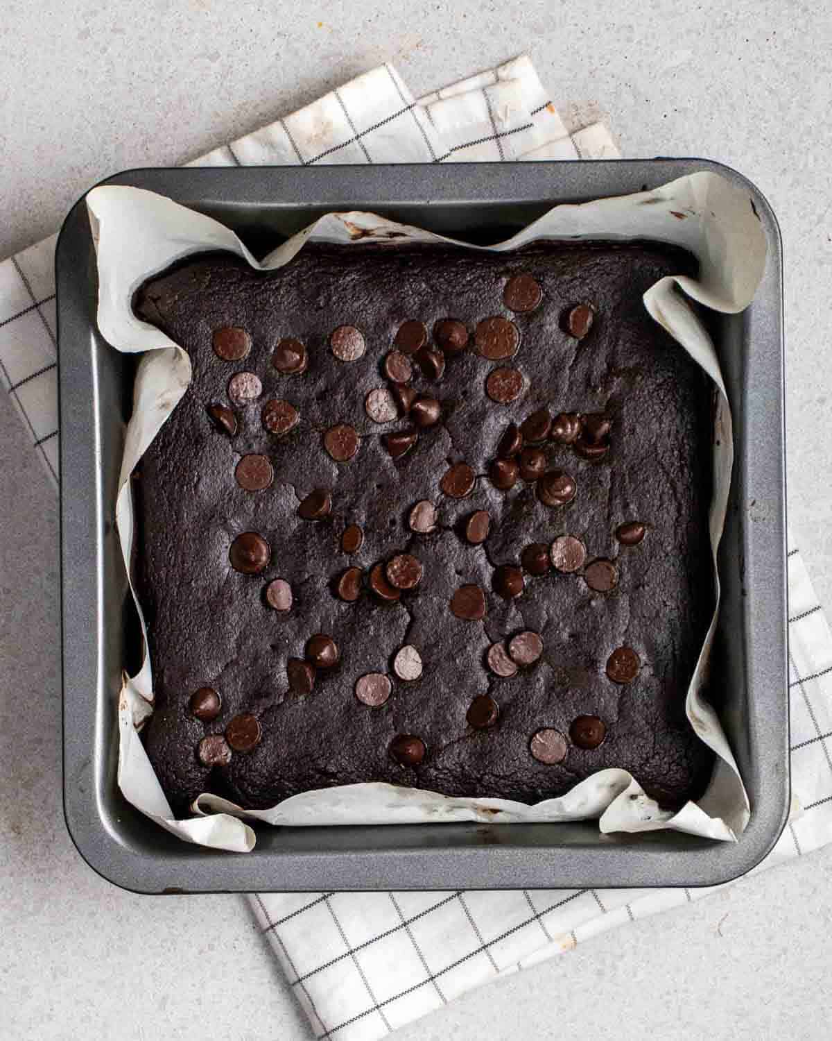 A tray of baked brownies on a white folded teacloth.