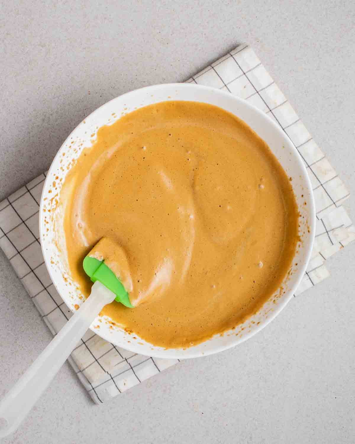 Wet ingredients for aquafaba brownies in a bowl with a spatula beside.