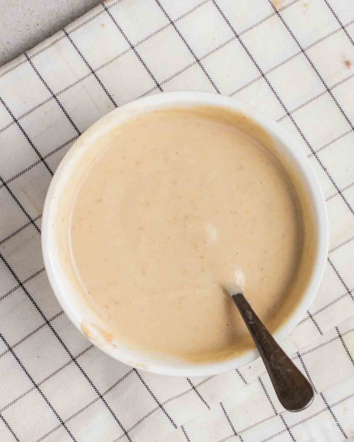 Wet ingredients for brownies in a bowl with a spoon beside.