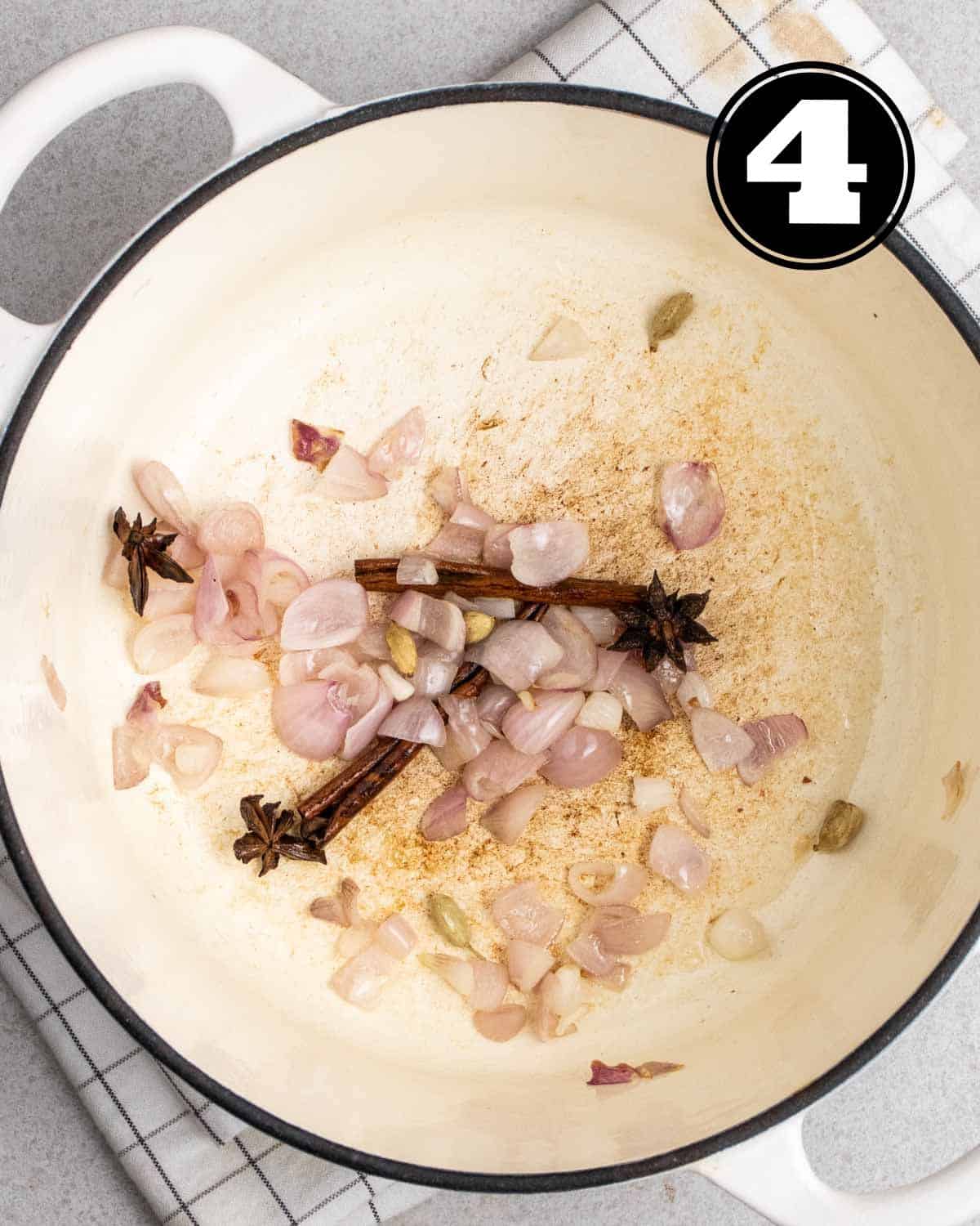 Cooked onion and spices in a white dutch oven.
