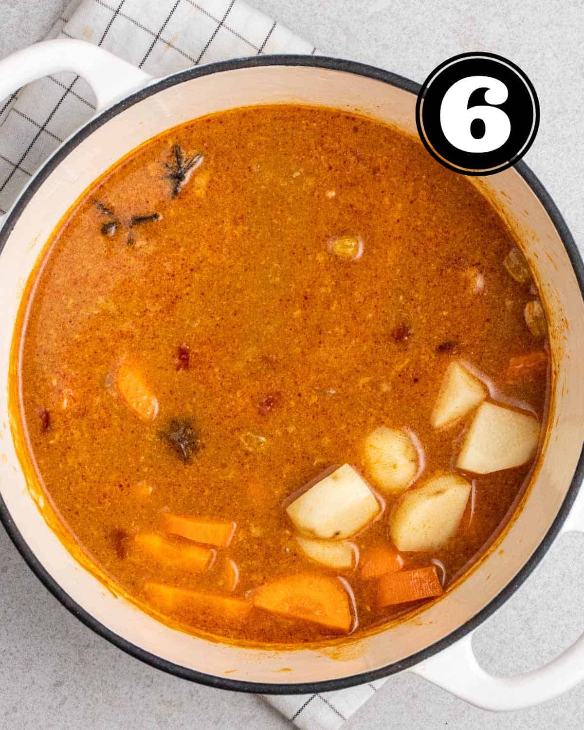 Cooked potatoes and carrot in a pot of curry sauce.