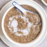 A bowl of mung bean soup served with a ceramic spoon on a plate.