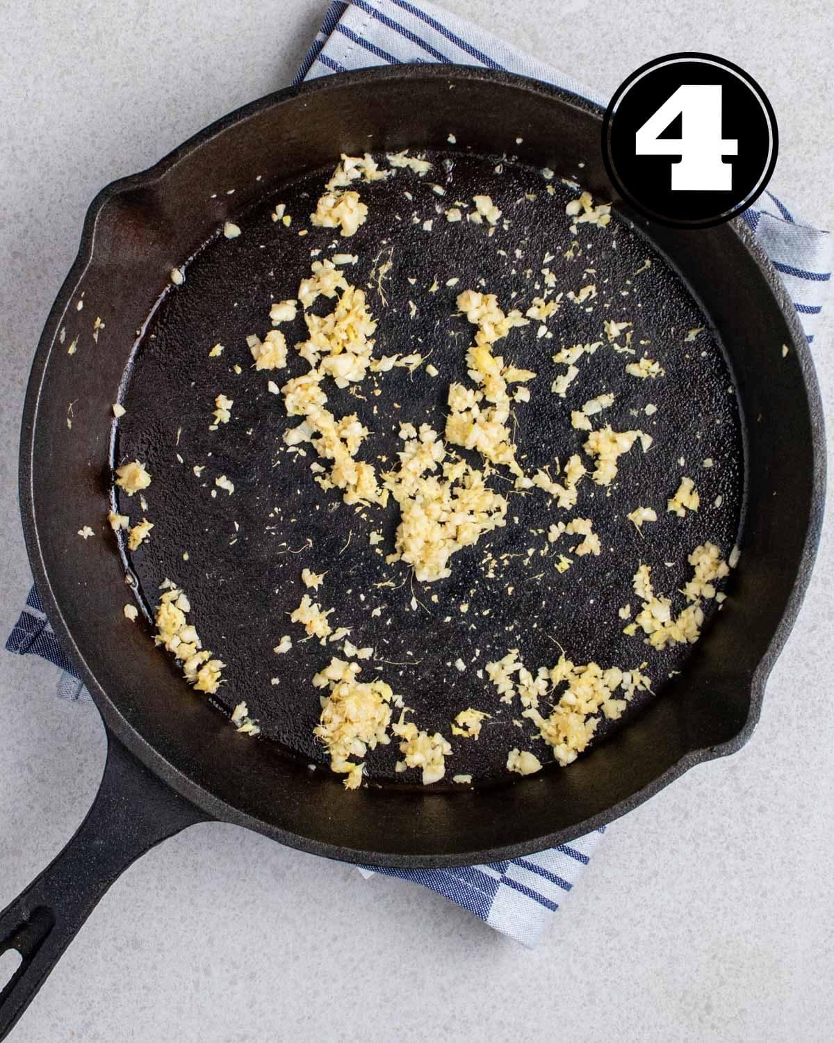Cook ginger and garlic in a cast iron skillet on a folded blue teacloth.