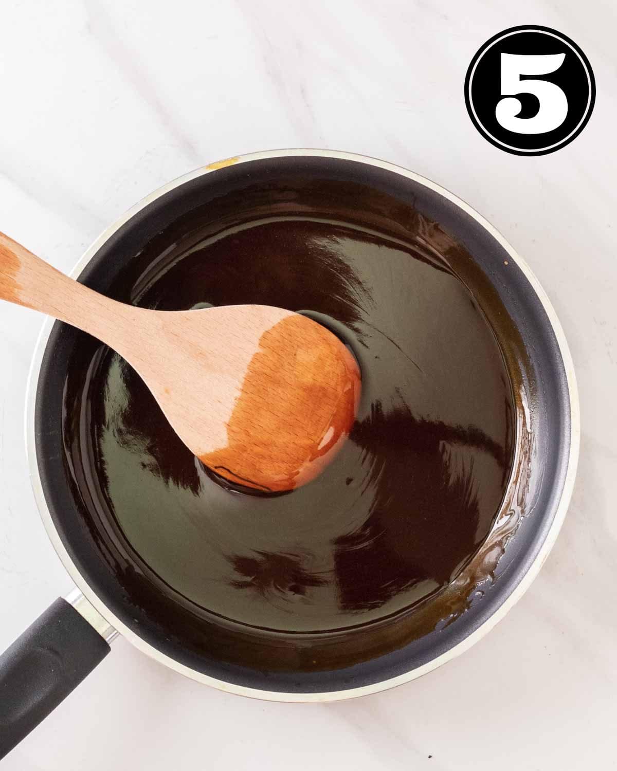 Cooked teriyaki sauce in a non-stick pan with a wooden spatula beside.