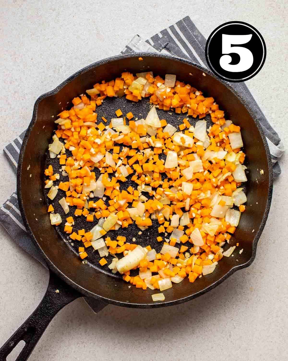 Cooked carrot, onion, and garlic in a pan.