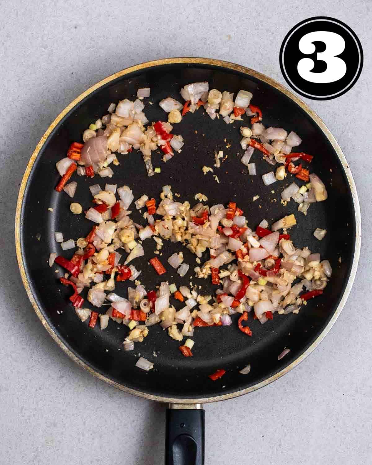 Cooked onion, lemongrass, garlic, and chilies in a black non-stick pan.