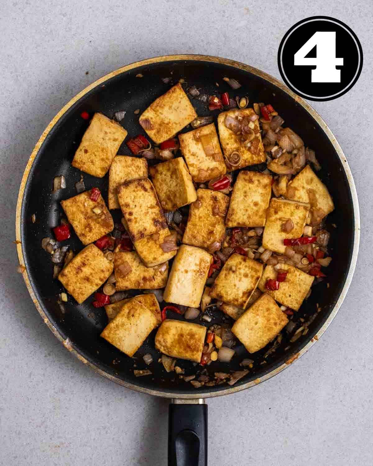 Lemongrass tofu in a black non-stick pan on a grey background.