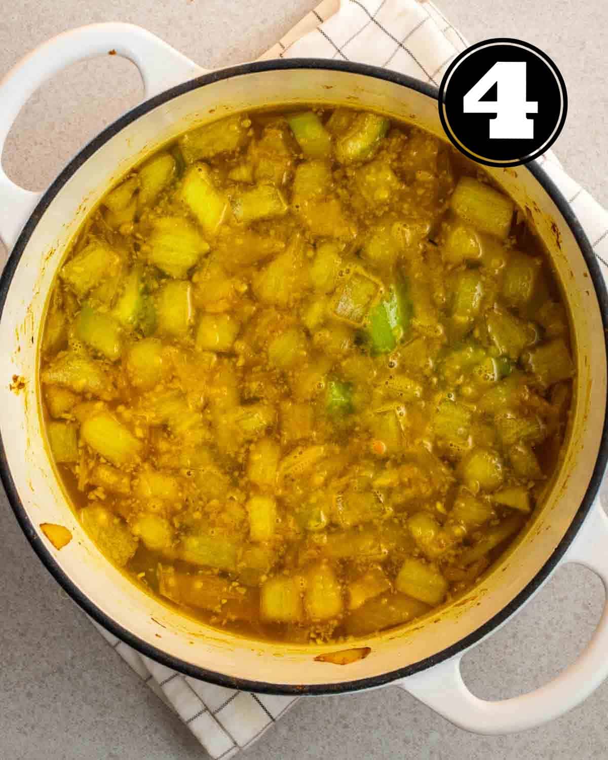Adding broth and lentils to a pot of browned vegetables.