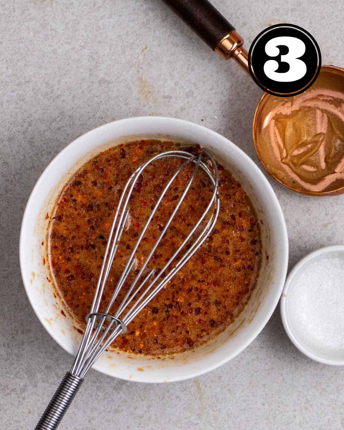 Peanut sauce for stir-fry in a ramekin with a whisk beside.