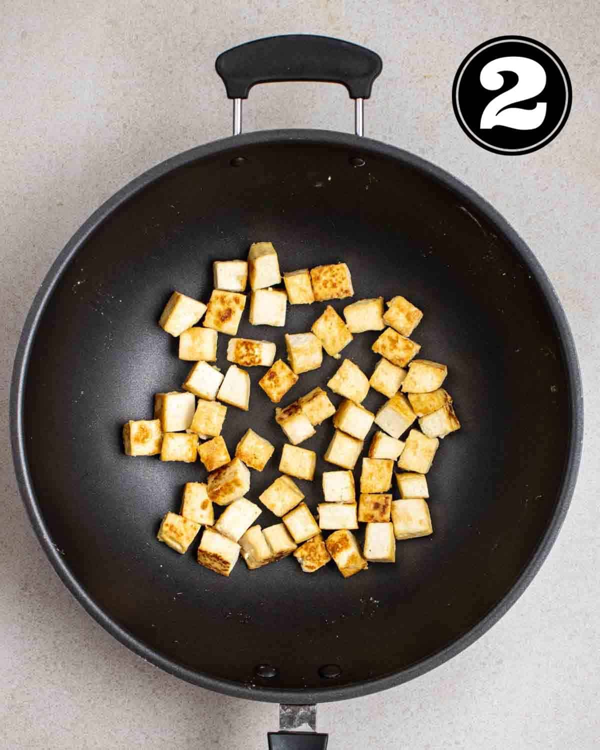 Pan-fried tofu in a wok.