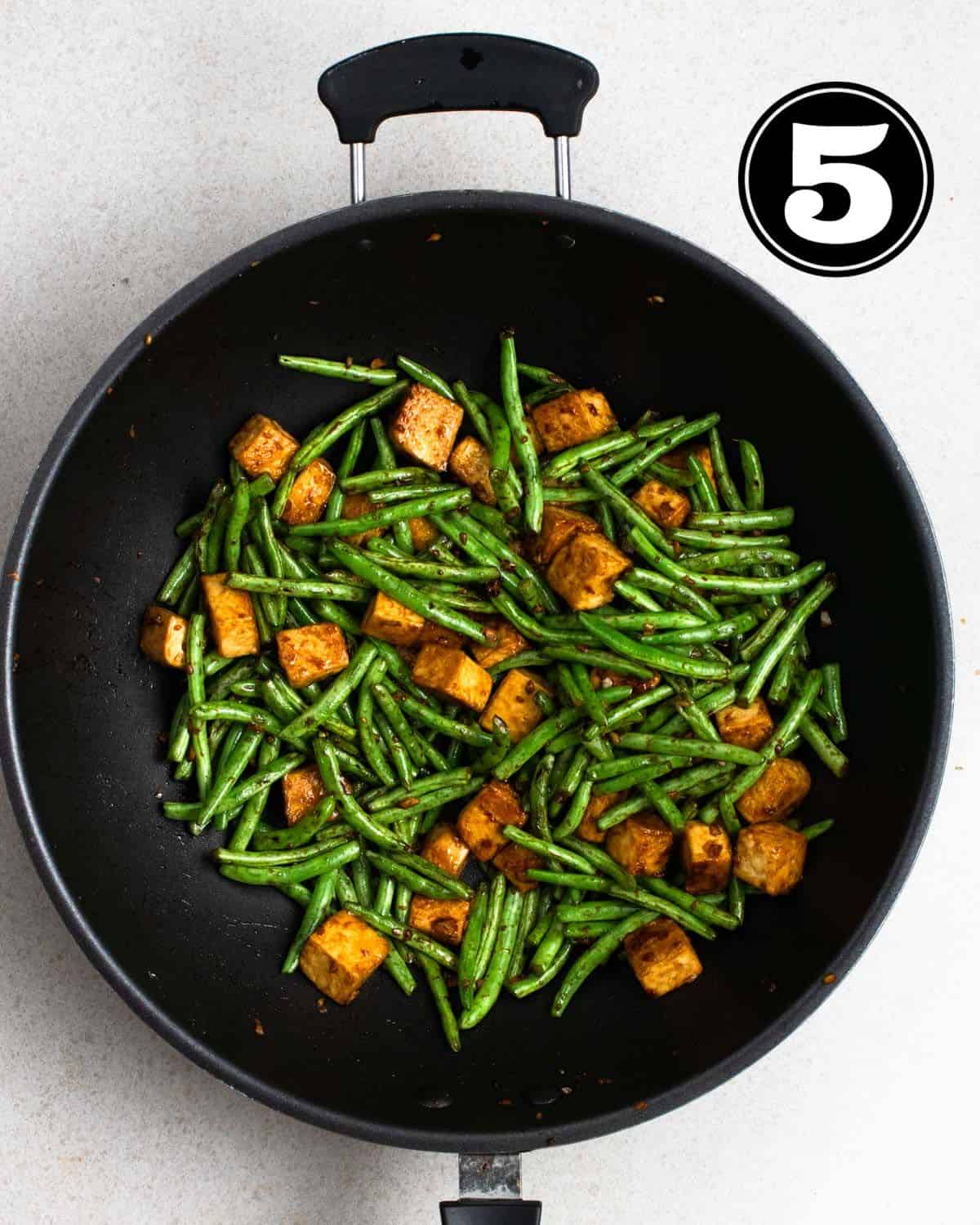 Green beans tofu stir-fry in a wok.