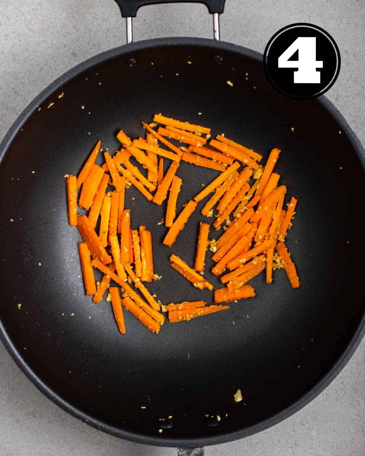 Cooked garlic and carrot in a wok.