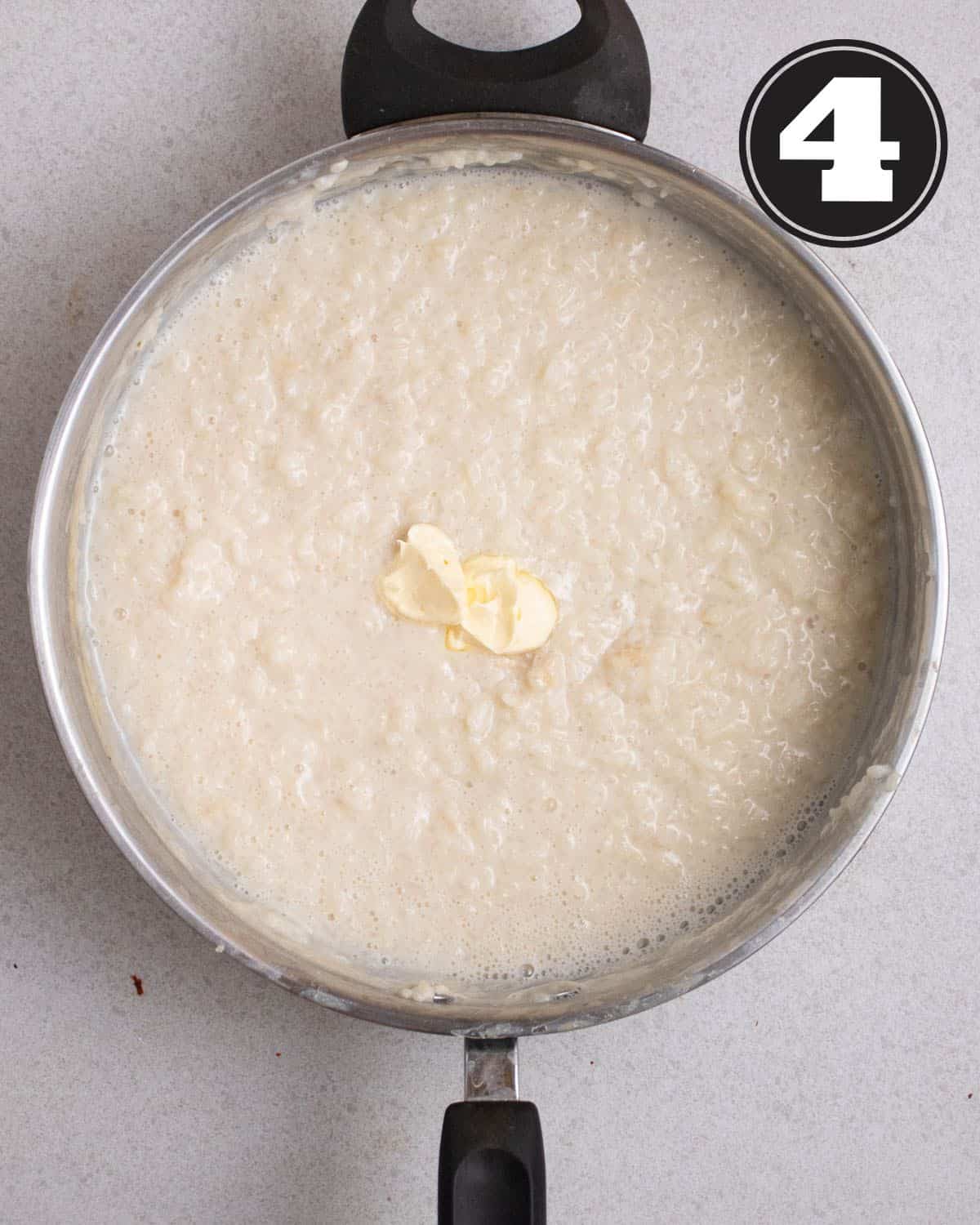 Adding a tablespoon of butter to a pan of cooked rice pudding.