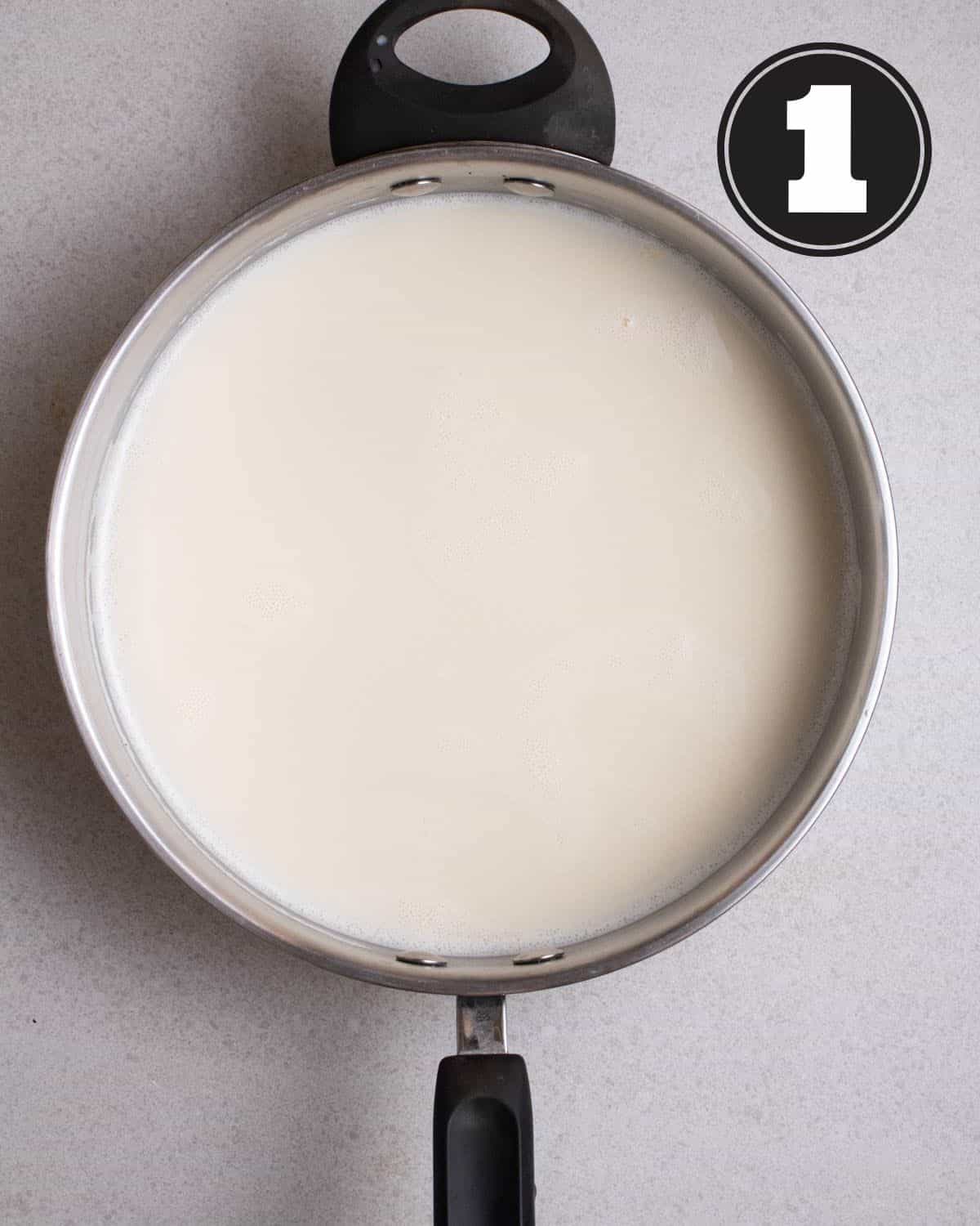 Almond milk in a aluminum pan on a grey background.