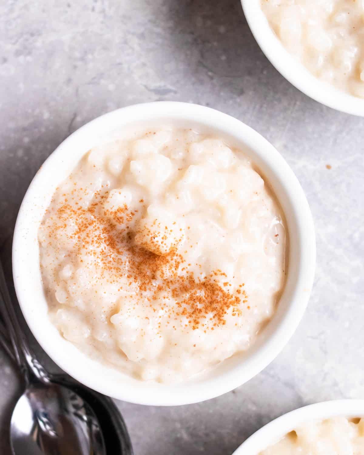 3 ramekins of rice pudding topped with ground cinnamon.