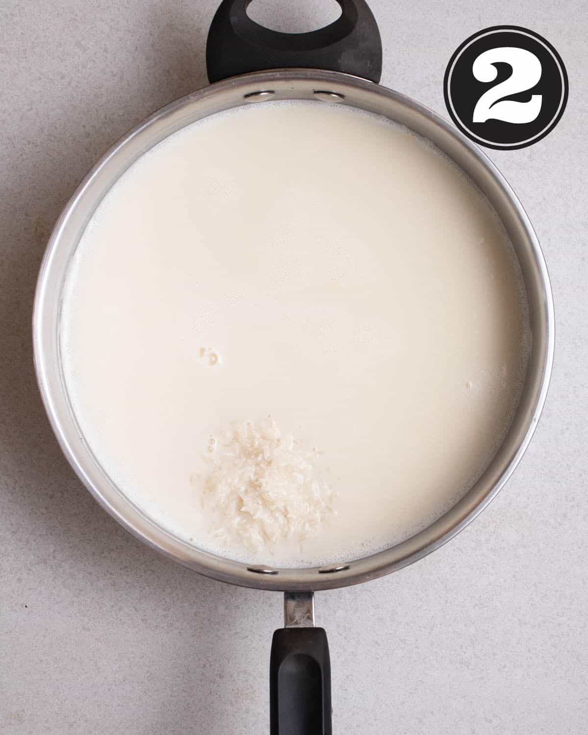 Raw rice added to a pan of almond milk. 